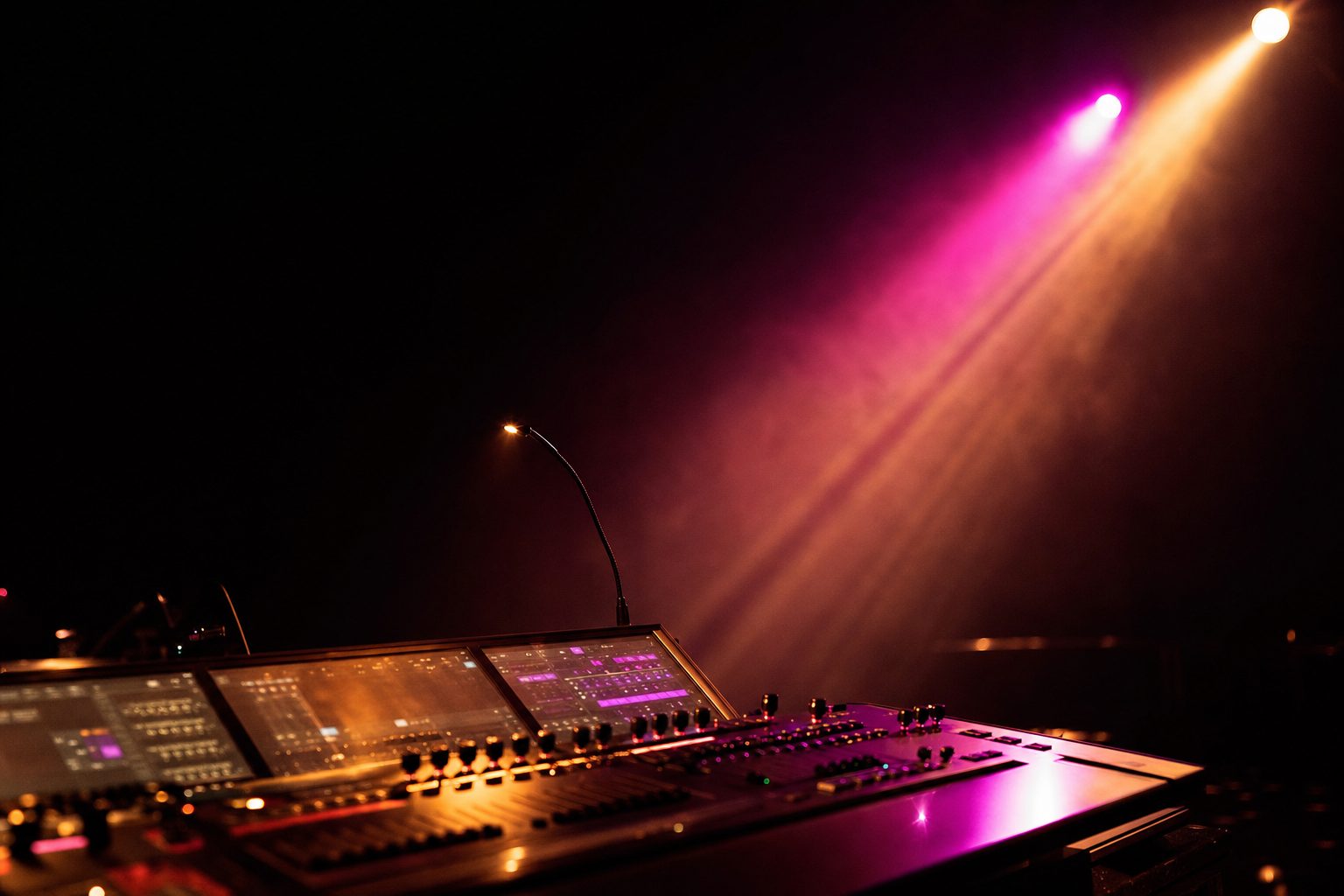 A dark edit suite with a wide monitor showing abstract magenta and amber motion graphics.