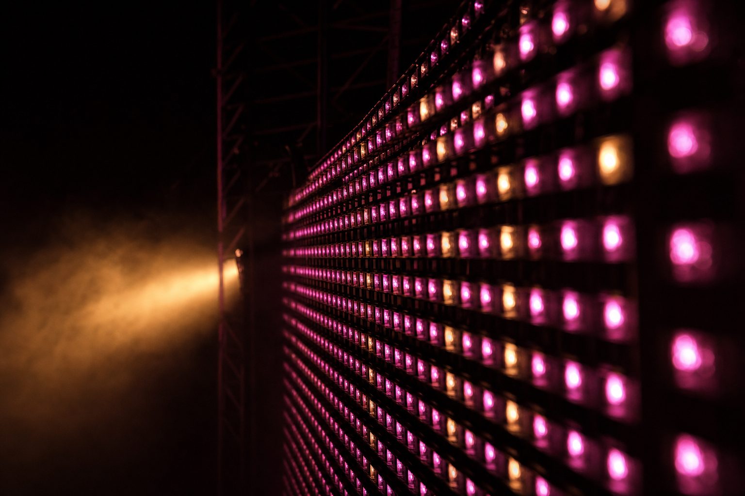 A close macro view of an LED panel showing the individual diodes at pixel pitch, glowing magenta and amber.