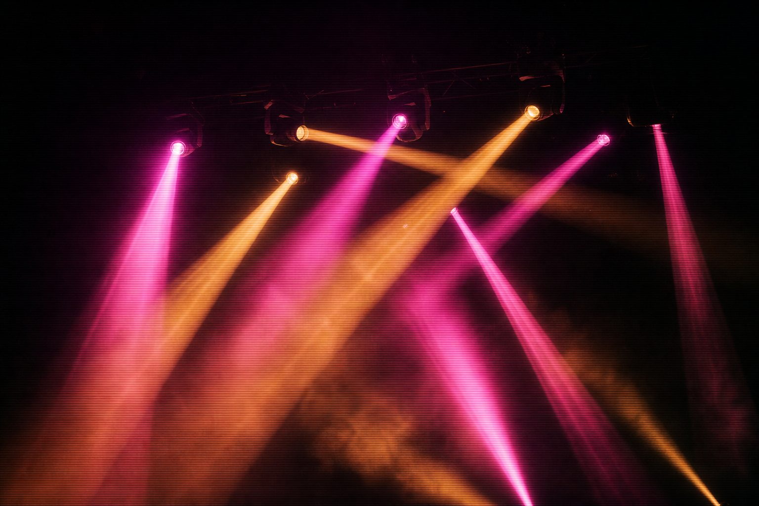 Moving-head fixtures on a bar, each pointing in a different direction, their beams crossing in haze.