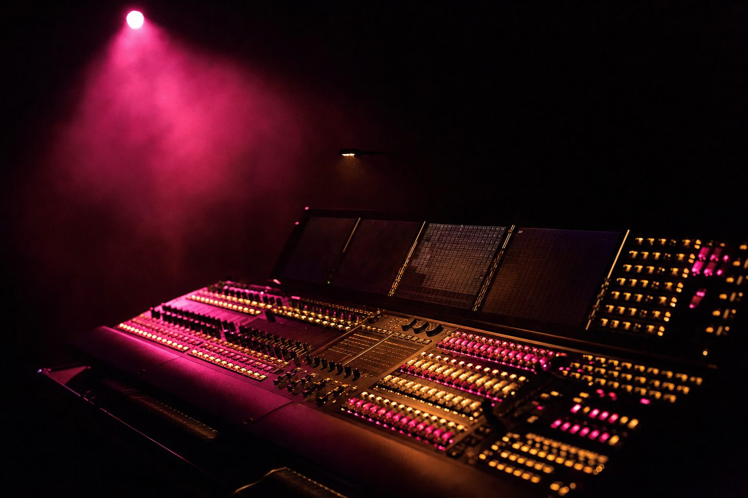 A lighting console covered in hundreds of small illuminated buttons in a dark room.