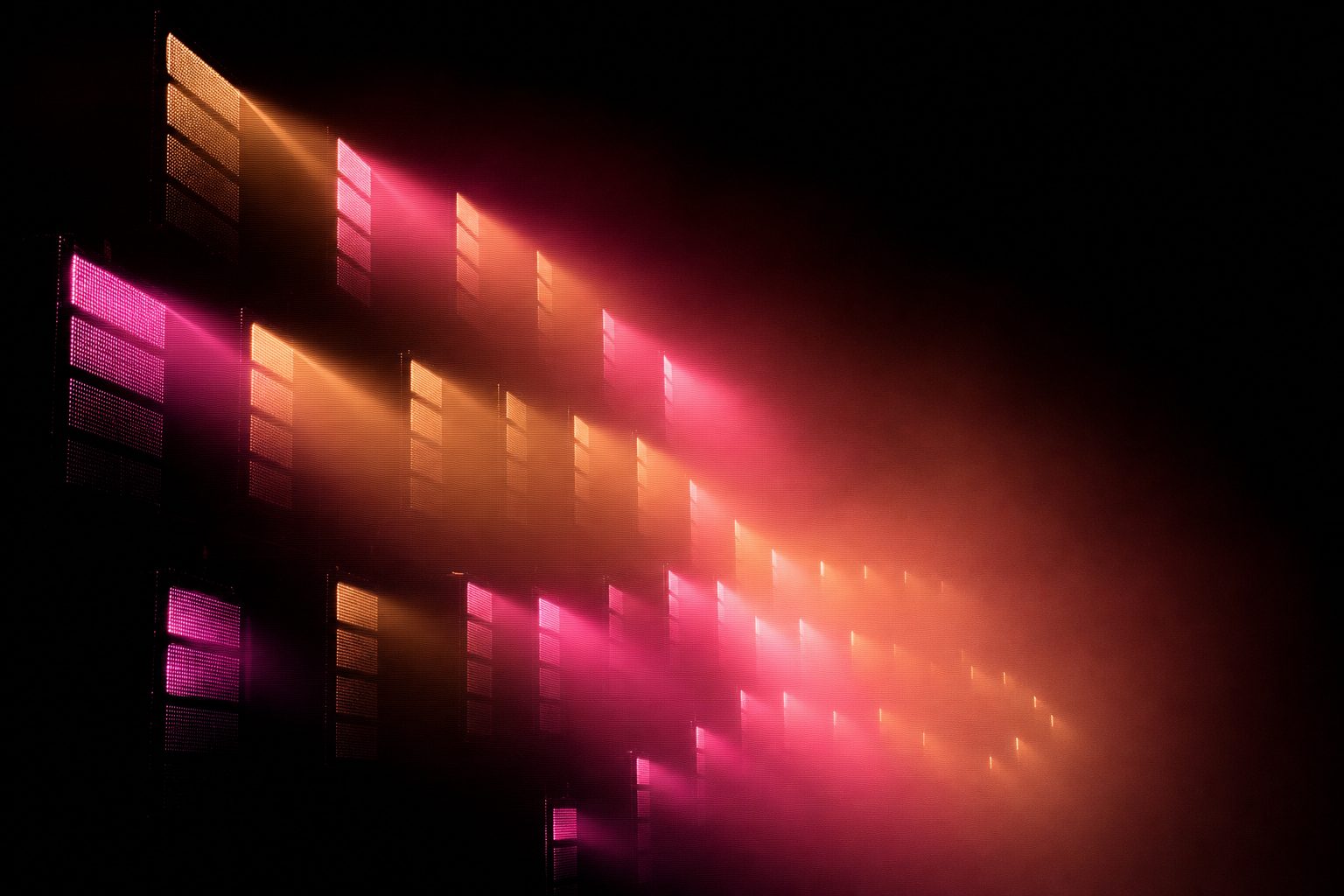 A wall of stacked light panels dissolving into haze and receding into black.