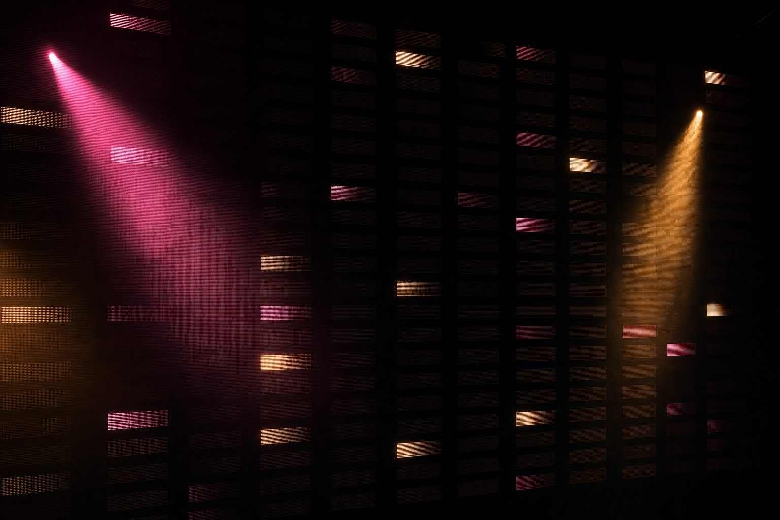 A tall wall of small rectangular light panels stretching across the frame, the great majority dark and only a scattered handful lit, so the wall reads as a record with most of it missing.