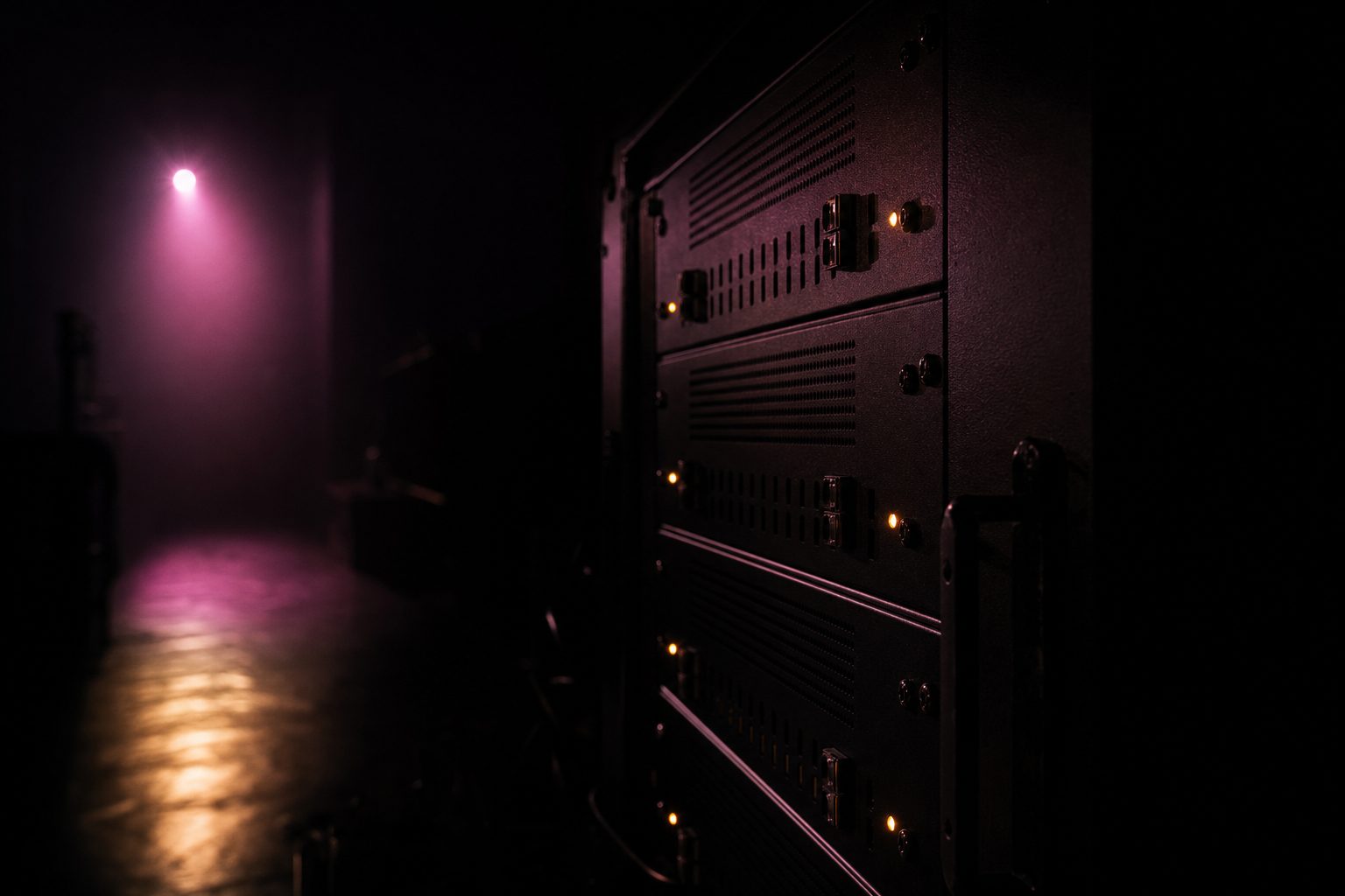 A closed dimmer rack in a dark corridor, its standby indicators glowing faintly amber.