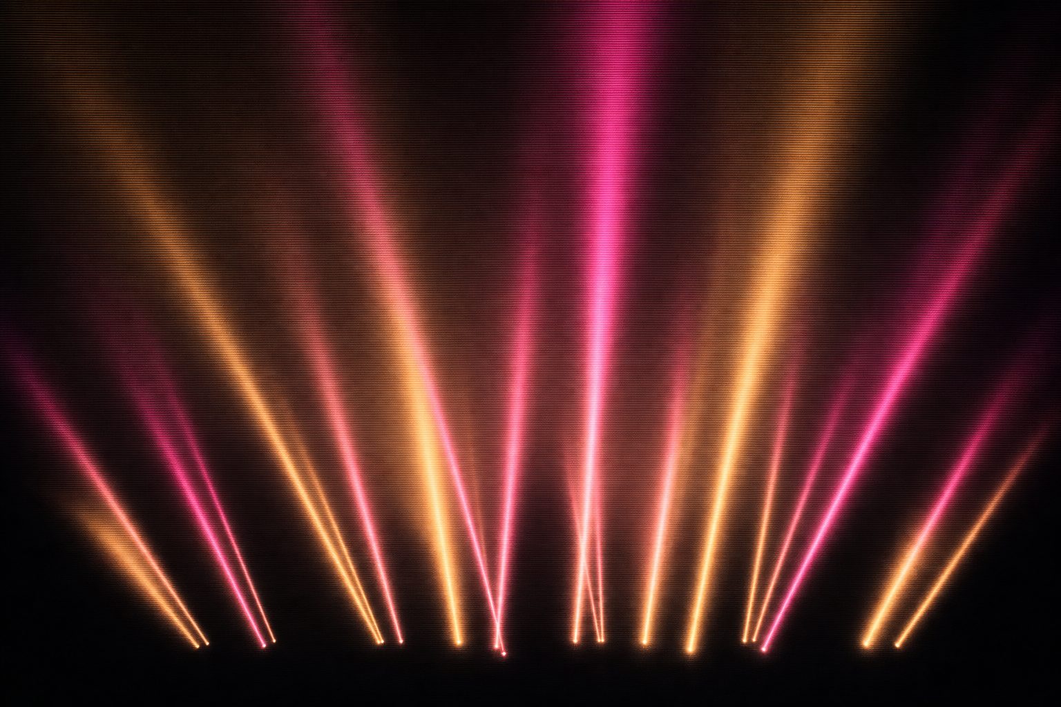 Many narrow beams rising from an open flat expanse into an enormous empty sky, spreading as they climb, the ground almost invisible below them.