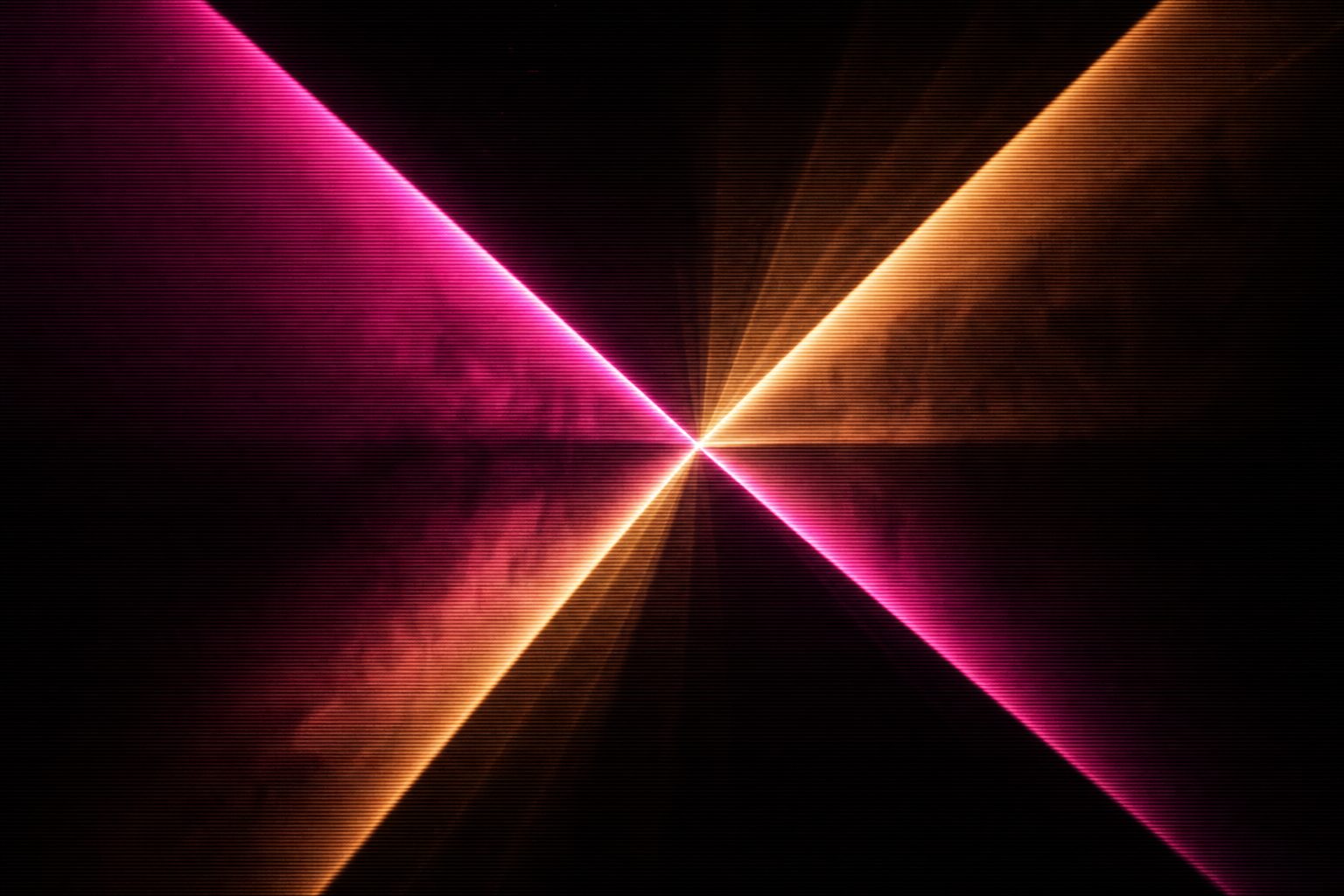 Hard triangular shafts of magenta and amber light crossing at a single point in dense haze.
