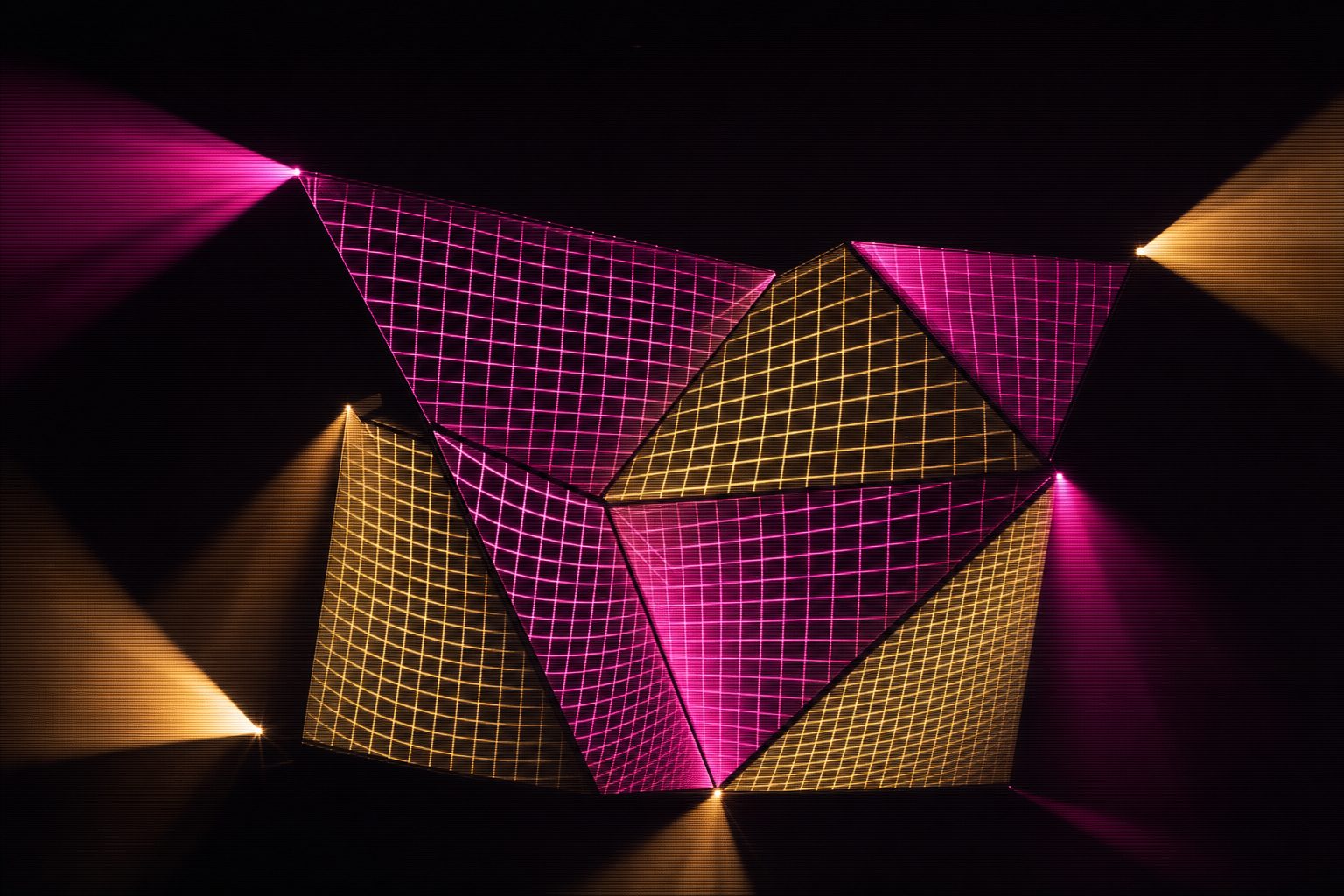 A bright calibration grid landing on a cluster of irregular angled panels, the grid corners visibly pinned and pulled so the squares distort to follow the geometry, black everywhere the grid does not fall.